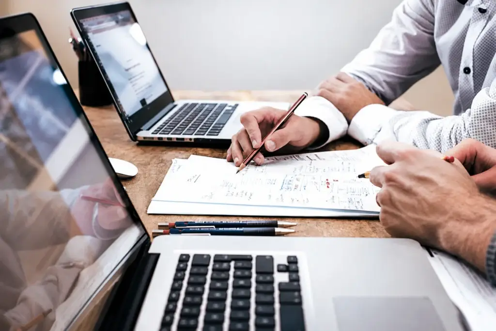 Professionals reviewing notes beside laptops